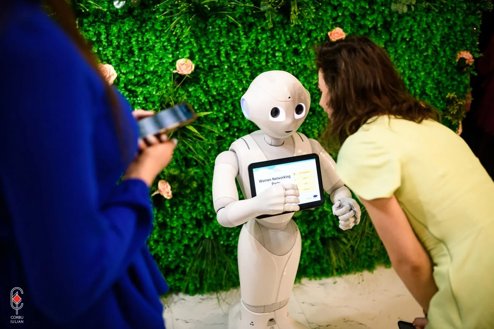 O vizitatoare folosește tableta robotului Pepper, iar o colegă filmează momentul