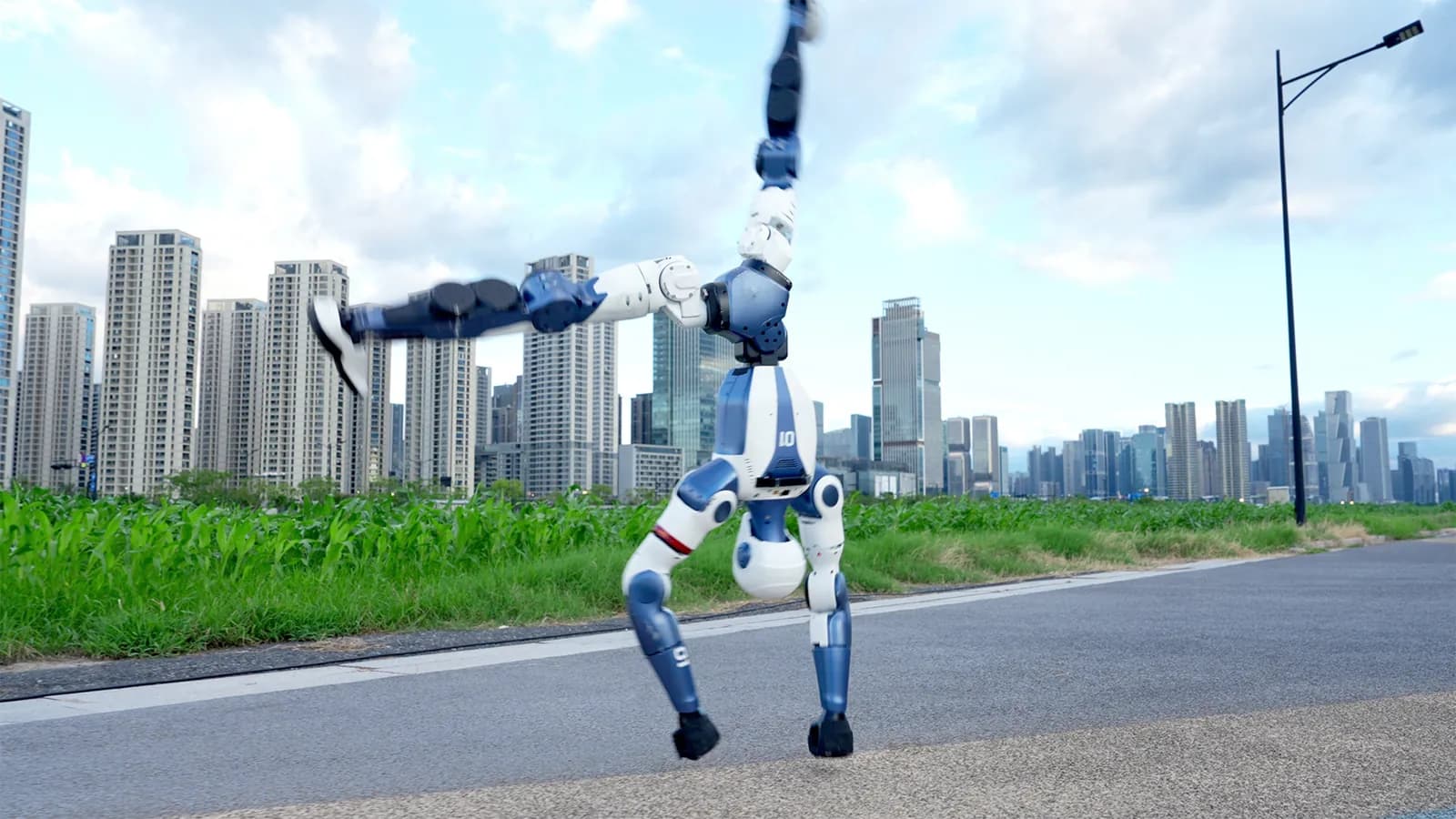 Robotul Unitree R1 stă în mâini pe asfalt, cu blocuri de locuințe în fundal